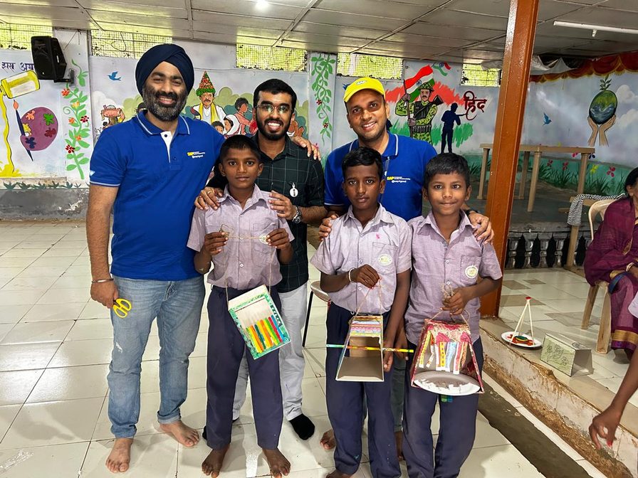 A SAP Labs volunteer with school children holding craft items